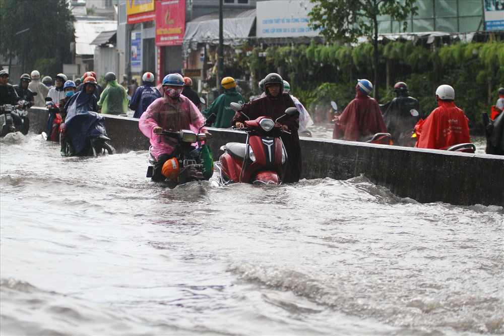 Nước ngập lút bánh xe máy trên đường Phạm Văn Đồng.  Ảnh: M.Q