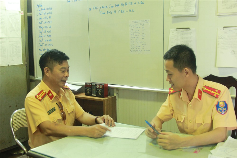 Thượng úy Phạm Đức Duy (phải) trao đổi công việc cùng đồng nghiệp. Ảnh T.Vương