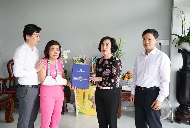 Đại diện Ban giám hiệu trường ĐH Hoa Sen trao bang tốt nghiệp cho bà Liên (áo hồng) mẹ của nam sinh Hải Nguyên