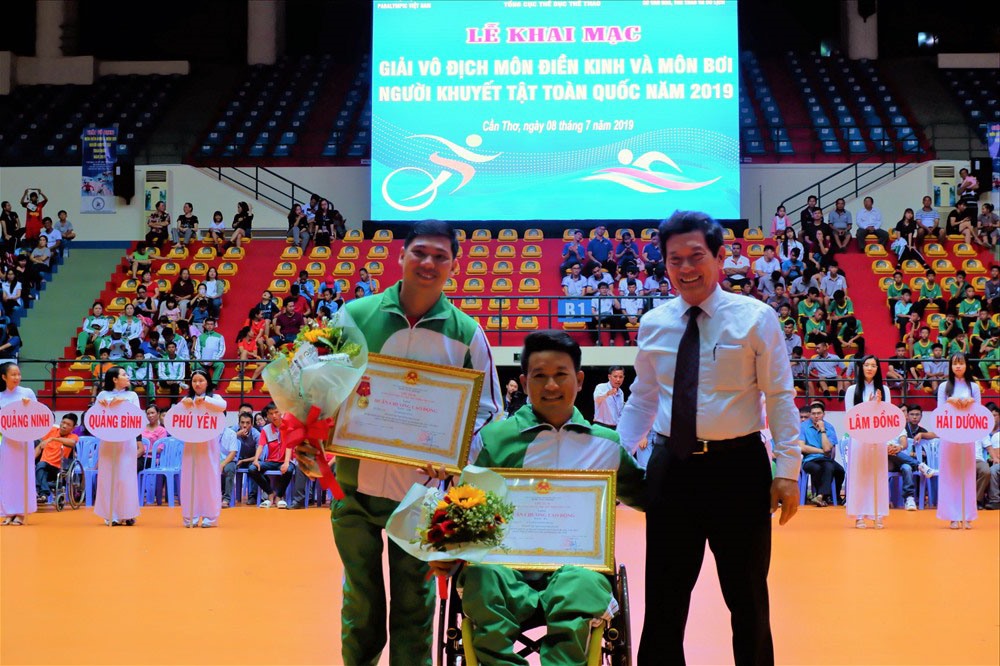 VĐV Võ Thanh Tùng (bên phải ngoài) nhận Huân chương Lao động hạng Nhì của Chủ tích Nước tại Lễ khai mạc môn thể thao và môn bơi lội người khuyết tật năm 2019 được tổ chức tại TP Cần Thơ. ảnh: Diệu Hòa