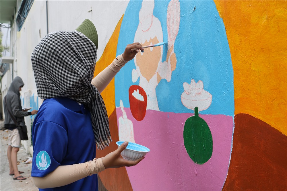 Một nữ “họa sĩ” tình nguyện đang say mê bên tác phẩm của mình.