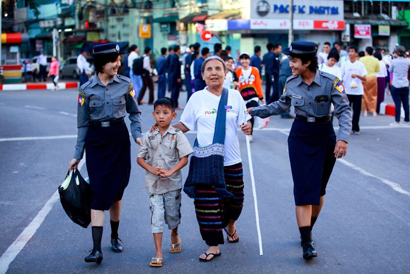 Hai nữ cảnh sát giúp một bà lão mù qua đường trên con phố nhộn nhịp ở Yangon, Myanmar.
