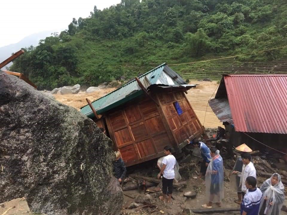 Người dân bên ngôi nhà hư hại do mưa lũ tại Mường Tè (Lai Châu)