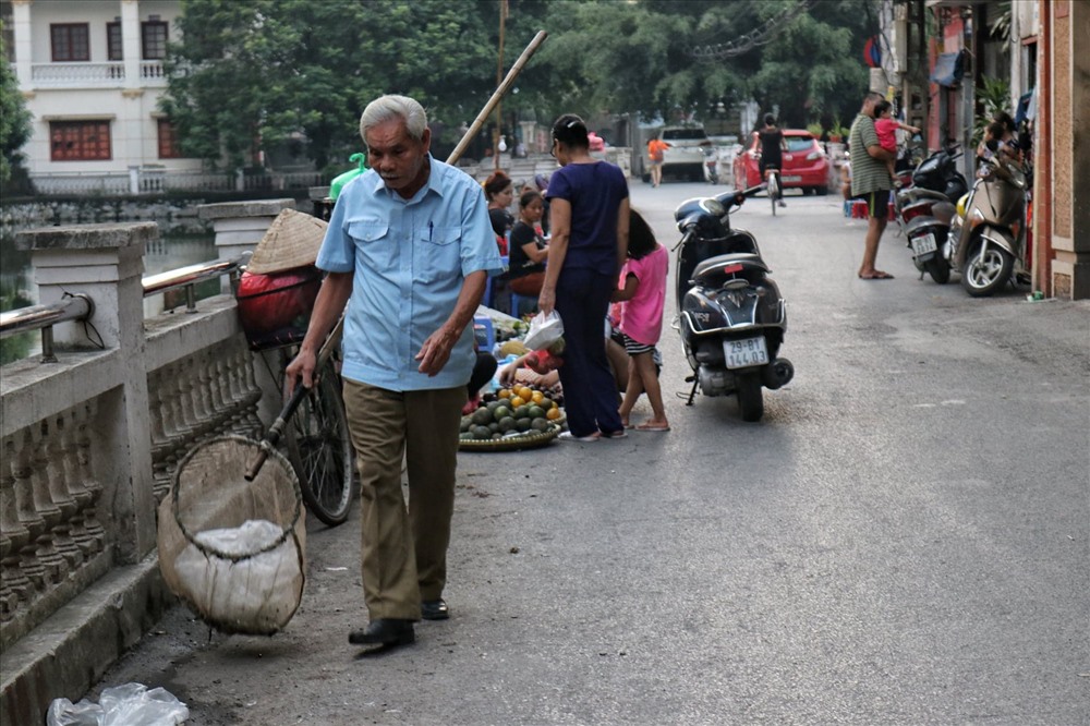 Sau khi chợ tan, ông Luyện lại thu gom rác rồi chuyển vào thùng.