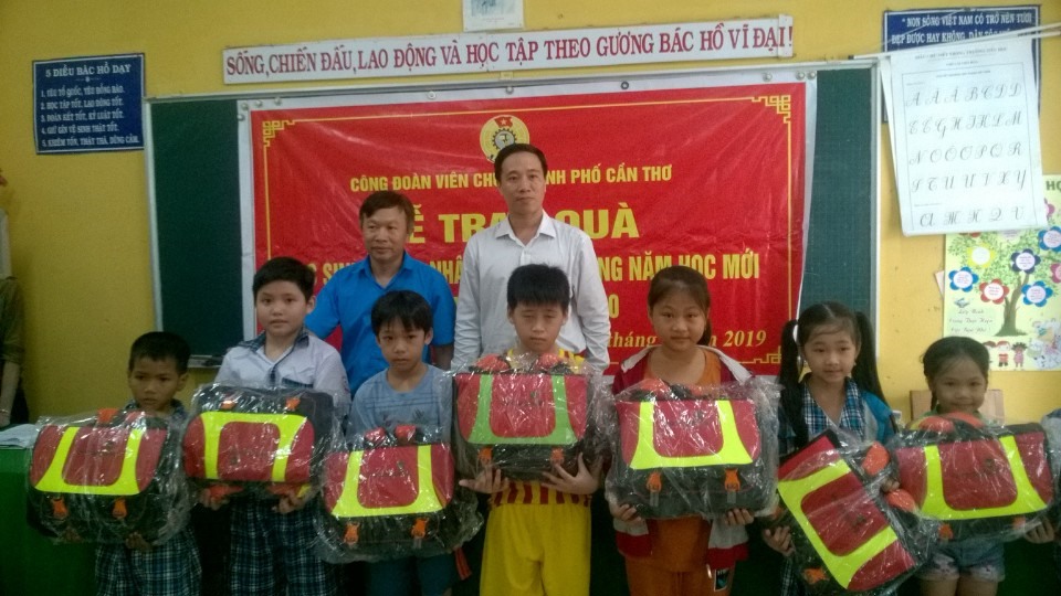 Ông Lê Văn Thừa và Ông Võ Phước Giang - trao quà và chúc mừng các em học sinh nhân quà. Ảnh: Thành Nhân