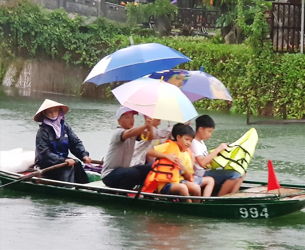 Khách lên thuyền ngoài áo phao còn phải trang bị thêm cả áo mưa và ô dù. Ảnh: NT