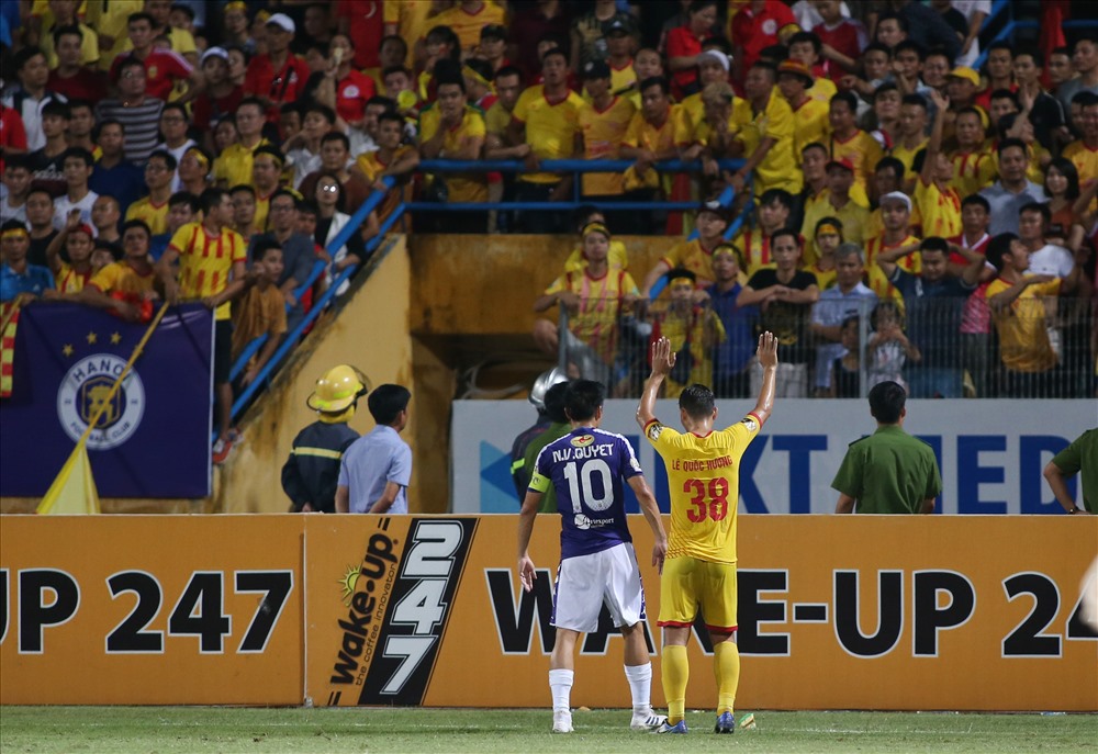 Cầu thủ Nam Định và Hà Nội giơ tay xin các CĐV không ném pháo sáng và vật thể lạ xuống sân. Ảnh: L.T
