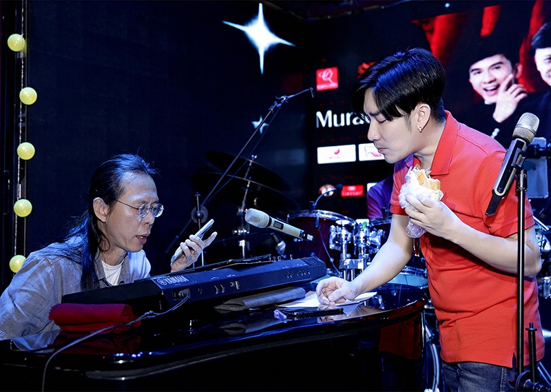 Quang Hà tranh thủ ăn bánh mì lót dạ trong khi tập cùng nhạc sĩ Nguyễn Quang.