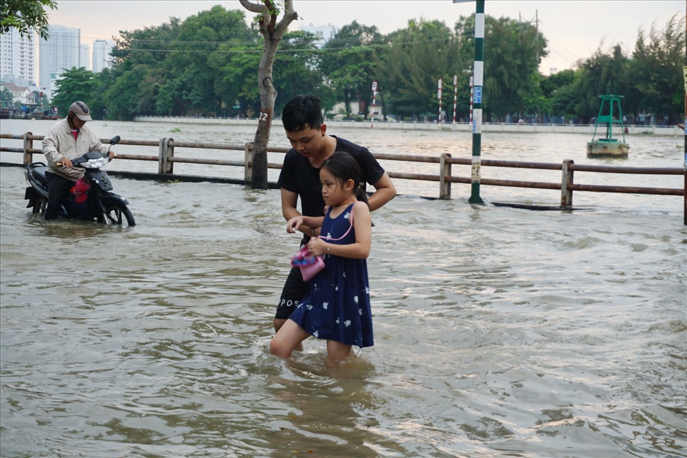 Anh Nguyễn Duy Khánh dắt em nhỏ vào vỉa hè, tránh đoạn đường ngập sâu.