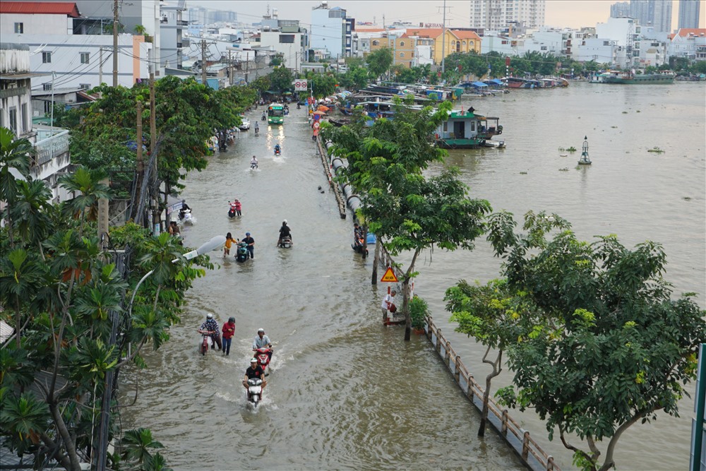 Chiều ngày 29.9, dòng nước đen ngòm, bốc mùi hôi thối từ dưới kênh Tẻ tràn bờ gây ngập đường Trần Xuân Soạn. Đường mênh mông nước không biết đâu là đường đâu là kênh.