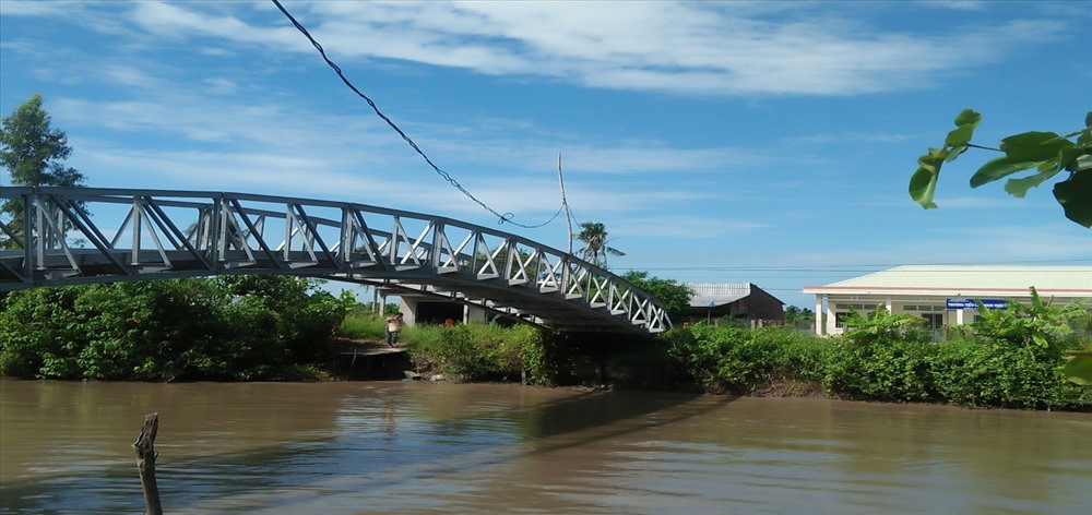 Dây diện kéo ngang sông một cách sơ sài với chiếc “cột điện’’ bằng tre nằm sát thành cầu sắt khá nguy hiểm. Ảnh: Mỹ Huyền