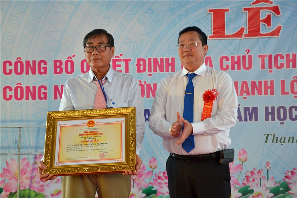 Ông Trần Quang Bảo (bìa phải) trao bảng công nhận Trường đạt chuẩn quốc gia của UBND tỉnh cho Trường THPT Thạnh Lộc. Ảnh: Lục Tùng