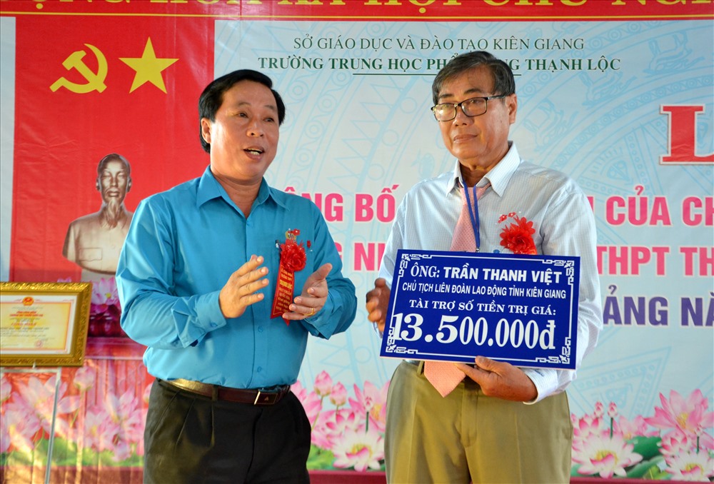 Chủ tịch LĐLĐ Kiên Giang Trần Thanh Việt (trái ảnh) trao biểu trưng 1.500 quyển tập cho Trường THPT Thạnh Lộc. Ảnh: Lục Tùng