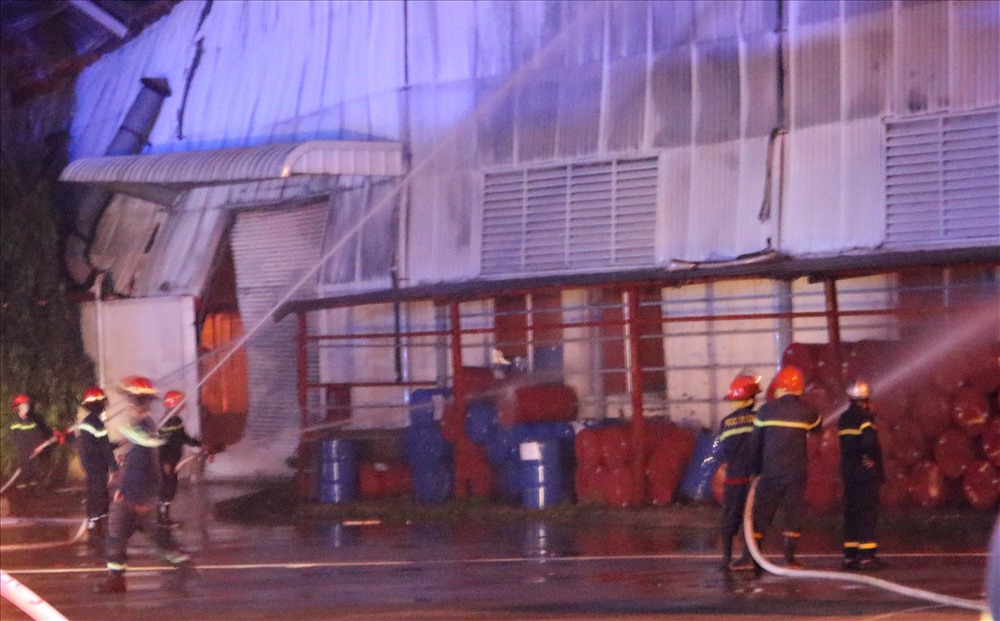 Lực lượng chữa cháy phun nước vào hàng chục thùng phuy ở bên ngoài nhà xưởng.