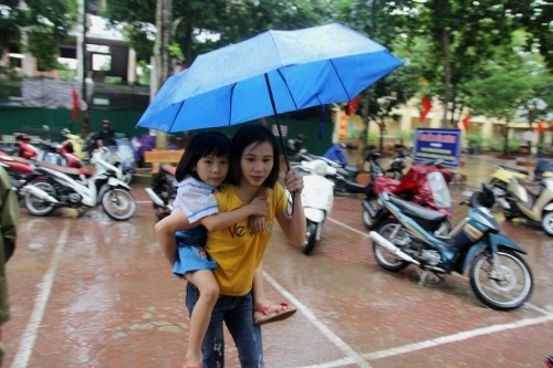 Mưa to, người mẹ cõng con đến trường tiểu học Hưng Dũng 1 (thành phố Vinh- Nghệ An) dự lễ khai giảng. Ảnh: Anh Ngọc
