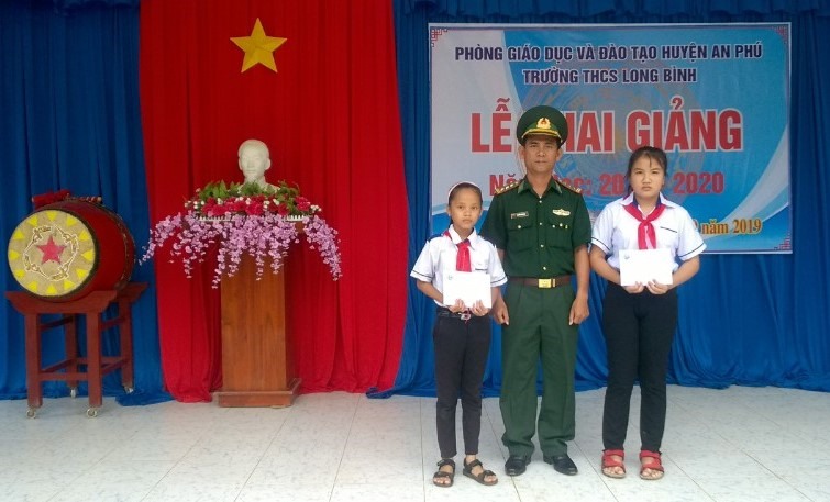 Ông Nguyễn Hoài Linh - Chính trị viên Đồn Biên phòng cửa khẩu Long Bình trao học bổng cho 2 em học sinh. Ảnh: Thành Nhân