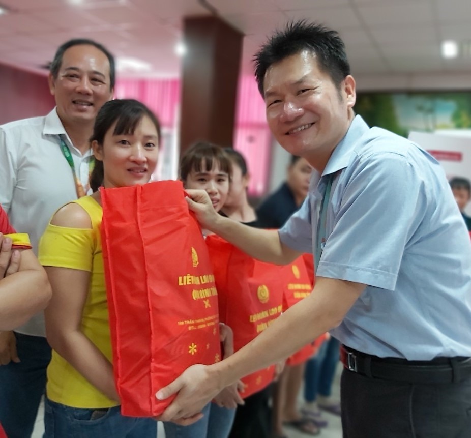 ông Lữ Khải Nguyên, Giám đốc Điều hành Công ty PouYuen (bên phải), tặng quà của LĐLĐ Quận Bình Tân cho các CNLDF9 có hoàn cảnh khó khăn của công ty. Ảnh Nam Dương