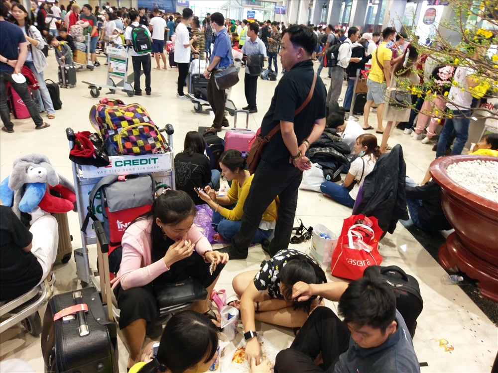 Một gia đình mang theo đồ ăn, ngồi bệt xuống sảnh ga quốc nội dùng bữa.