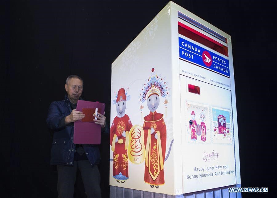 Một người đàn ông chụp ảnh cùng hòm thư in hình chủ đề Canh Tý tại trung tâm văn hoá Trung Quốc ở Toronto, Canada ngày 16.1.2020. Ảnh: Xinhua