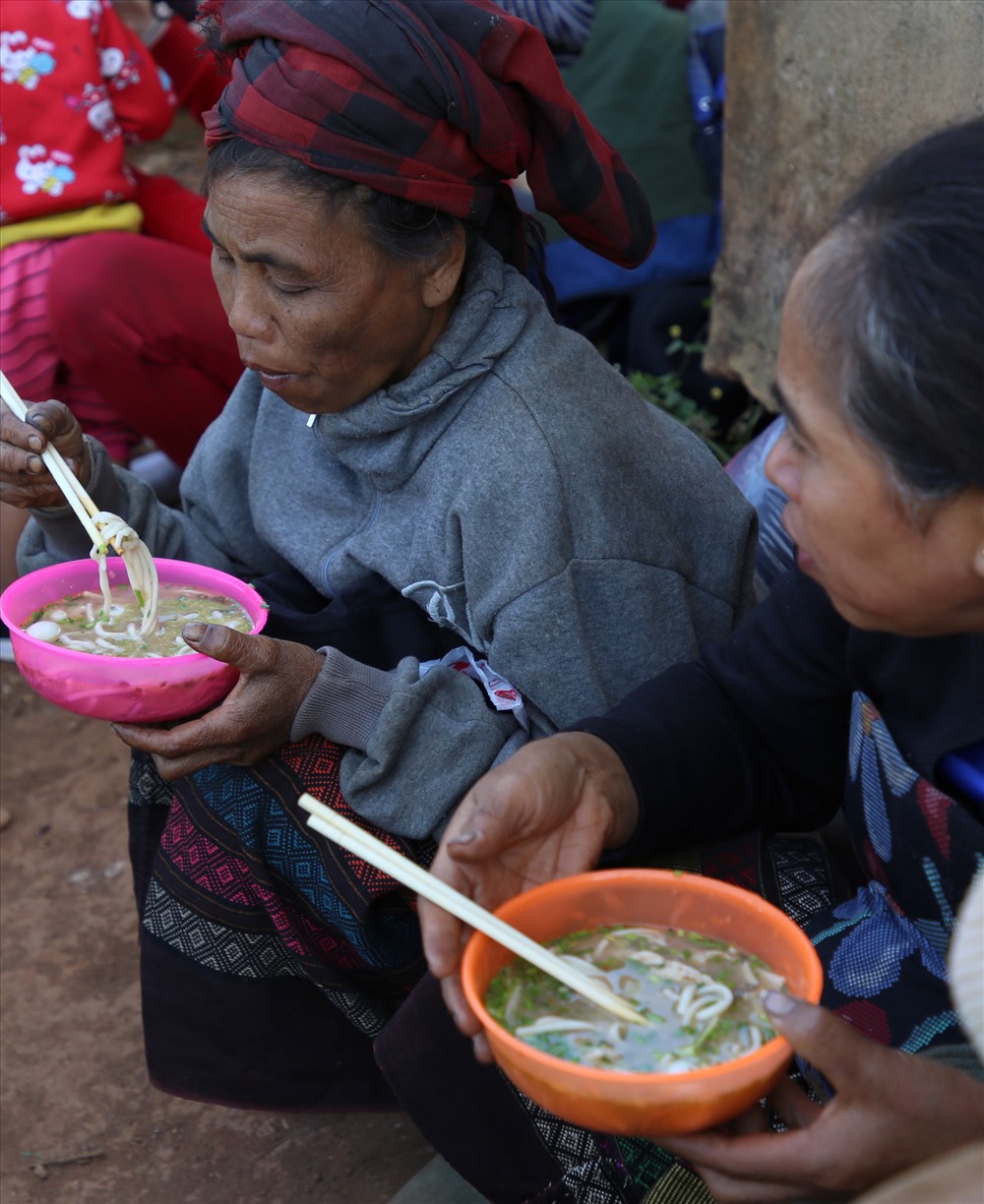 Bà Hồ Thị Nghị (bìa phải ảnh; 50 tuổi, trú ở thôn Doa Củ) nói rằng “lần đầu tiên ăn tô cháo ngon như ri“. Ăn no, bà Nghị đi về nhà lấy nồi nhôm, xin thêm để dành cho buổi tối.