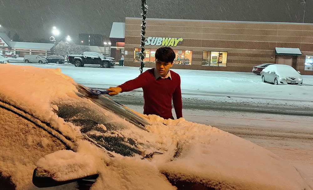 Một nhân viên người việc làm tại nhà hàng của chị Linh tranh thủ ra dọn tuyết rơi đầy trên xe ôtô của mình.