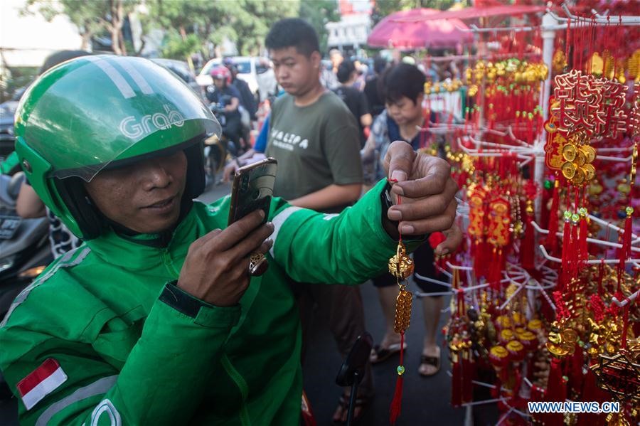 Tài xế Grab ở chụp ảnh cùng đồ trang trí ở chợ Pancoran, Jakarta, Indonesia ngày 22.1. Ảnh: Xinhua