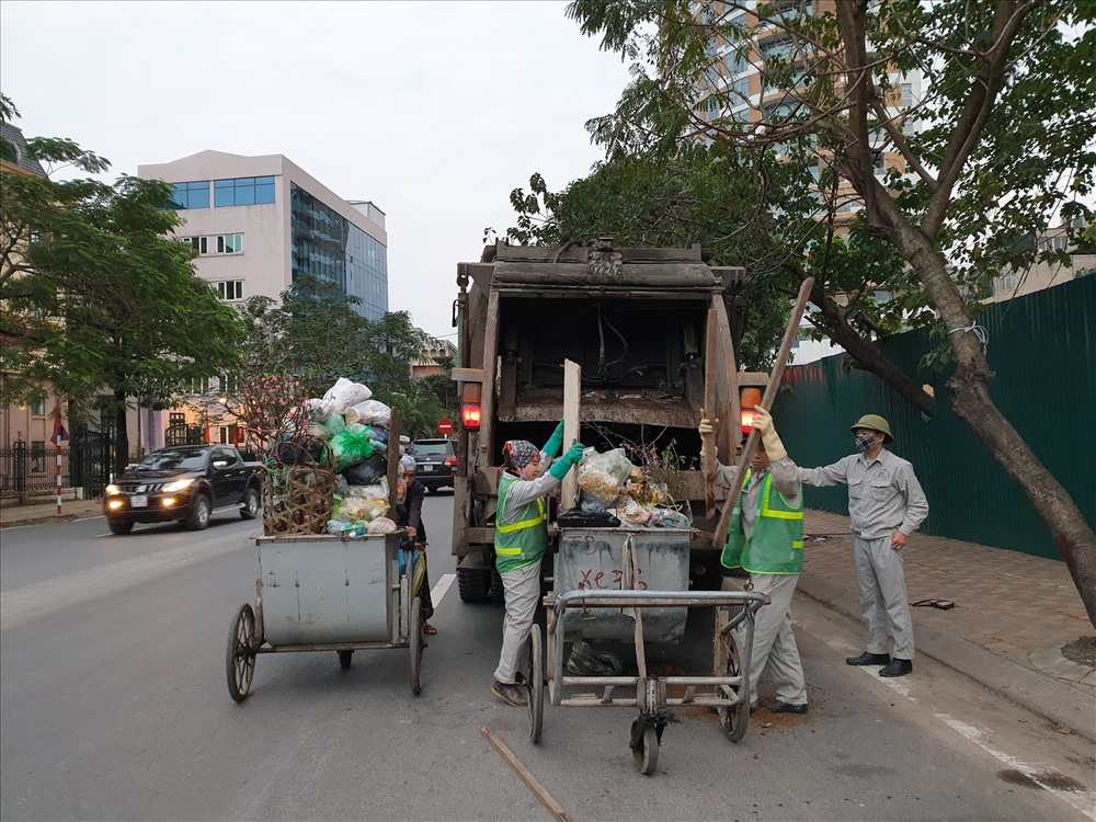 Theo anh Nam, anh bắt đầu ca làm việc từ 16h đến 0h sáng. Vì lượng rác chủ yếu là rác thải sinh hoạt nên rất nặng và khó di chuyển. Tuy nhiên, guồng quay chỉ thực sự bắt đầu sau hôm mồng 5 và kéo dài đến tháng giêng vì đào quất, rác thải sinh hoạt lại tiếp tụp phải thu gom trong những ngày sau Tết. Ảnh: Tùng Giang.