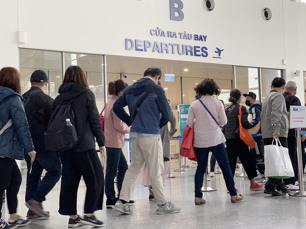 Tại cửa ra sân bay quốc tế T2, đoàn khách quốc tế sau khi làm thủ tục xuất cảnh mọi người đồng loạt đeo khẩu trang, tránh nói chuyện.