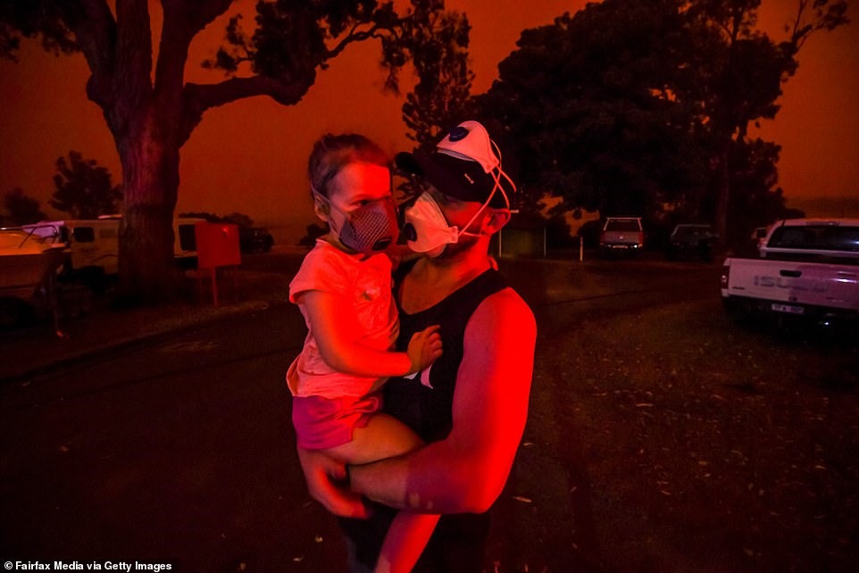 Hai mẹ con người dân đeo khẩu trang chống khói bụi khi bầu trời chuyển màu đỏ vào trưa ngày 4.1 tại Mallacoota, Victoria.
