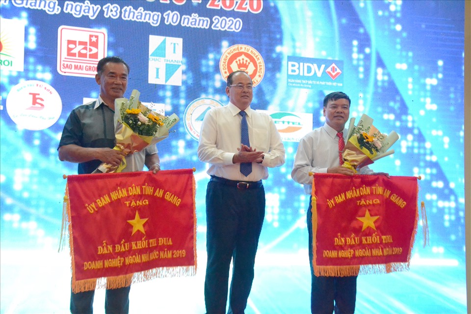 Chủ tịch UBND tỉnh An Giang Nguyễn Thanh Bình tặng cờ Đơn vị dẫn đầu doanh nghiệp ngoài Nhà nước. Ảnh: Lục Tùng