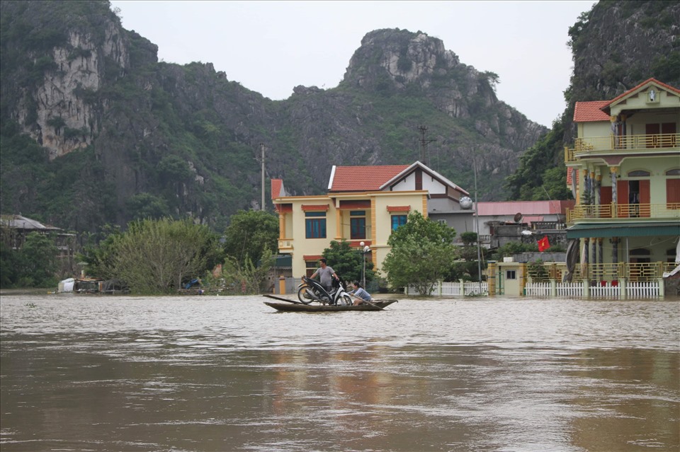 Người dân dùng thuyền để đưa người và xe máy qua những tuyến đường bị ngập lụt. Ảnh: NT