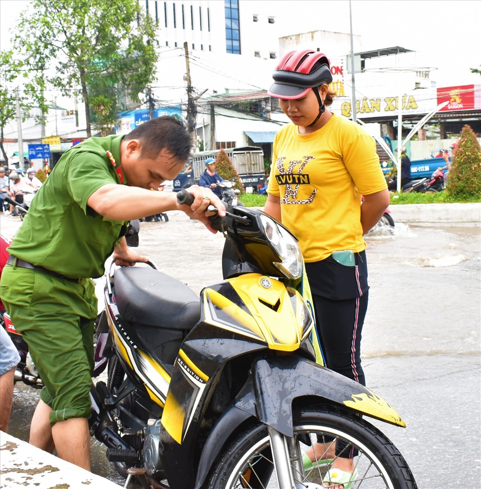 Nhiều xe chết máy do nước ngập trên đường Nguyễn Văn Cừ (quận Ninh Kiều), Công an phường An Khánh giúp người dân sửa xe. Ảnh: Thành Nhân