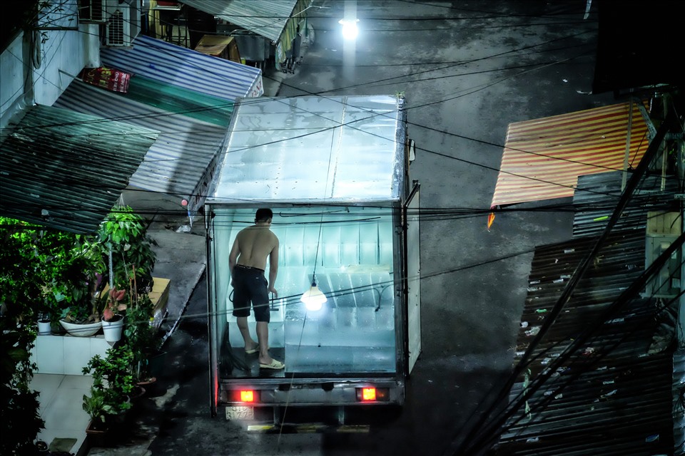 Một người chuyển nước đá cho một hộ kinh doanh bên dưới tầng trệt vào ban đêm.