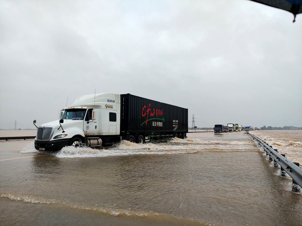 Các loại xe khách, xe tải đường dài được phép qua đoạn đường ngập lụt. Riêng xe con và các phương tiện cỡ nhỏ chưa được phép. Ảnh: Quách Du