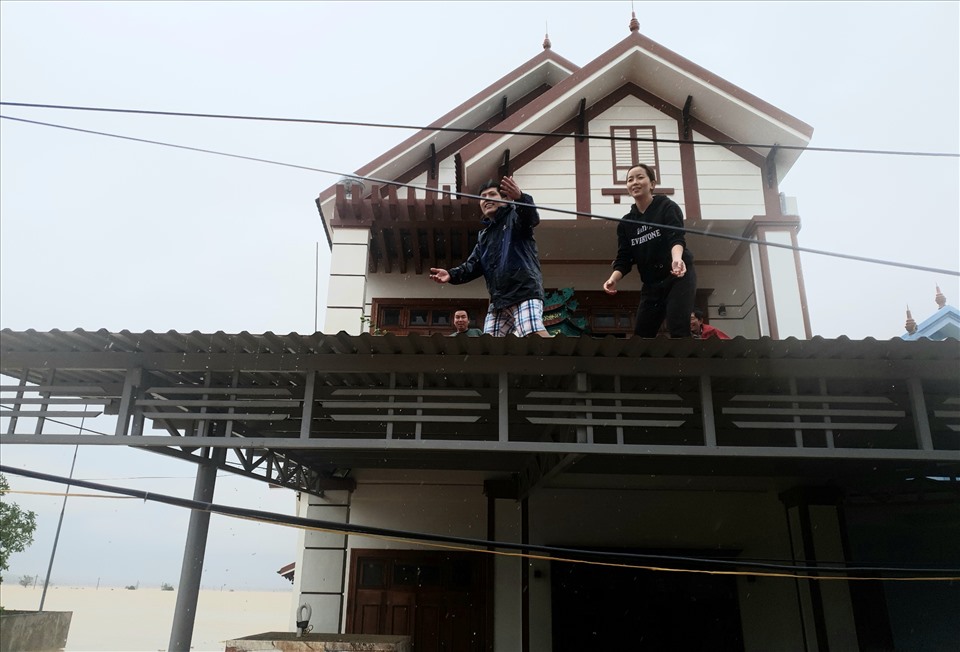 Dân trốn lũ trên mái nhà gọi hàng cứu trợ sáng nay 21.10. Ảnh: LPL
