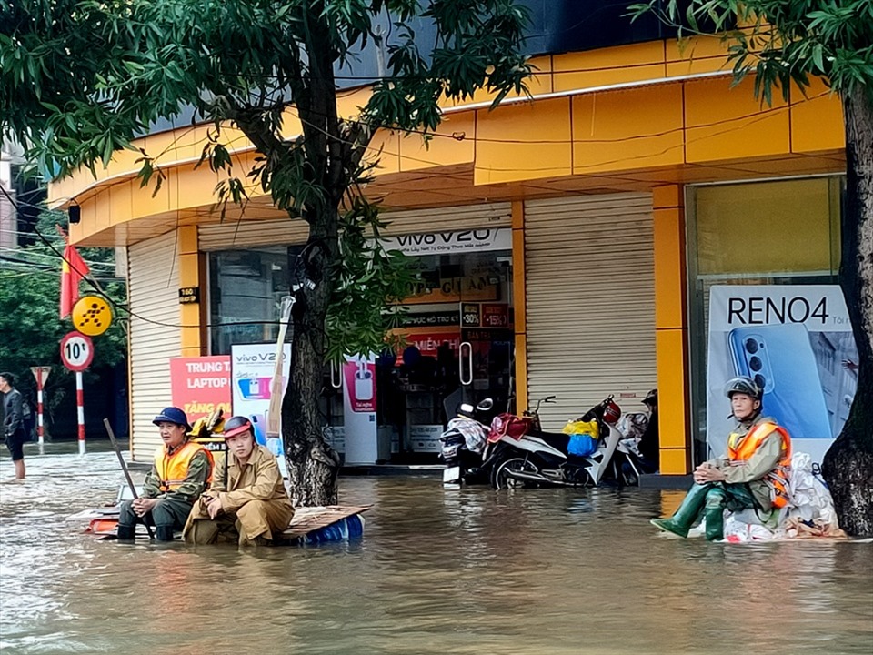 Người dân TP. Hà Tĩnh ngồi thất thần trước dòng nước lũ trên đường Hà Huy Tập. Ảnh: Quách Du