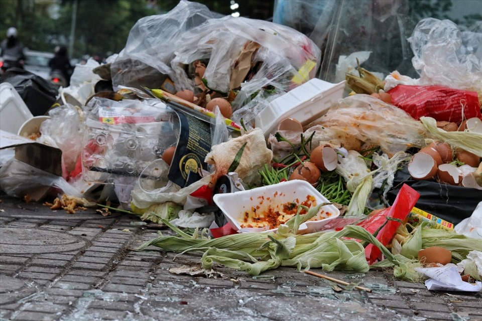 Lượng rác tồn đọng quá lớn đã tràn xuống lòng đường phố, ảnh hưởng đến quá trình đi lại của người dân. Ảnh: Lan Nhi.