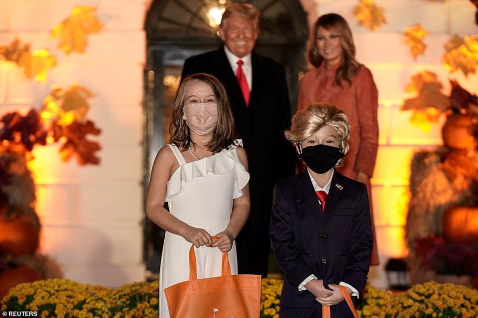 Hai trẻ hóa trang thành vợ chồng Tổng thống Donald Trump và phu nhân chụp ảnh cùng ông Donald Trump và bà Melania Trump tại một lễ kỷ niệm Halloween ở Nhà Trắng. Ảnh: