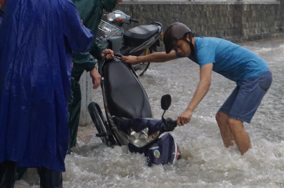 Một người đi xe máy bị sụp hố ga phải nhờ người dân hỗ trợ kéo xe máy lên. Ảnh: Minh Quân