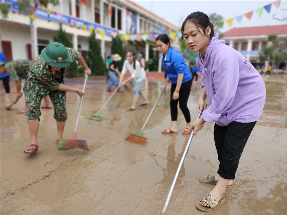Ngoài các cán bộ chiến sĩ, các thanh niên tình nguyện cũng được huy động đến để giúp trường dọn dẹp bùn đất sau lũ. Ảnh: Quách Du