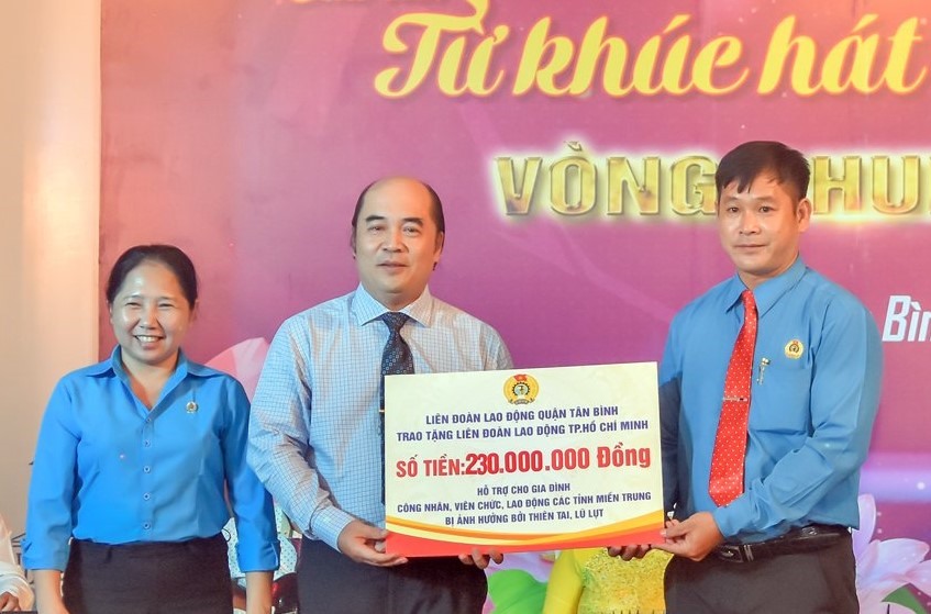 Ông Hồ Xuân Lâm (thừ hai từ trái qua), Phó Chủ tịch LĐLĐ TPHCM tiếp nhận bảng tượng trưng số tiền ủng hộ gai đình CNVCLĐ miền Trung bị thiên tai, lũ lụt. Ảnh Đức Long