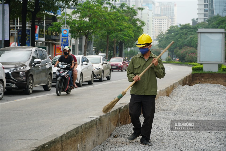 Các công nhân tiến hành dọn dẹp mặt bằng, quét dọn đá sỏi tránh rơi vãi ra đường để chuẩn bị di chuyển công trình ngầm nổi tại nút giao Tố Hữu - Khuất Duy Tiến.