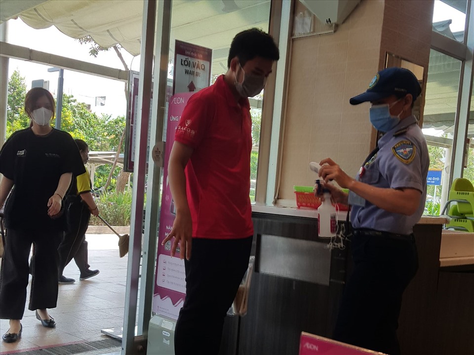 Lực lượng bảo vệ trung tâm thương mại AEON nhắc nhở khách đến đeo khẩu trang và xịt nước rửa tay sát khuẩn. Ảnh: Nguyễn Huy