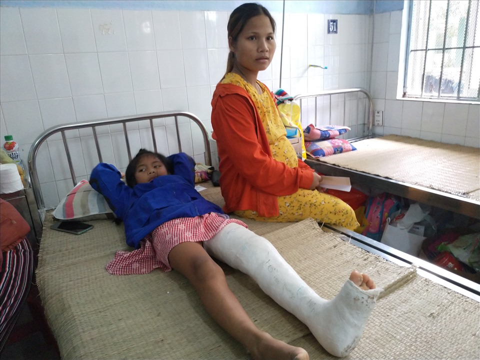 Chị Hồ Thị Hà chăm sóc đứa con bị gãy chân, trong khi chồng chị chăm sóc đứa con khác cũng bị thương nặng. Ảnh: k.q
