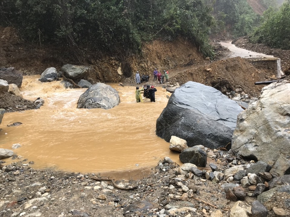 Nhiều khu vực bị nước lũ tràn qua đường, chính quyền xã Phước Thành huy động lực lượng dân quân khiêng xe máy giúp người dân. Ảnh: Anh Ky