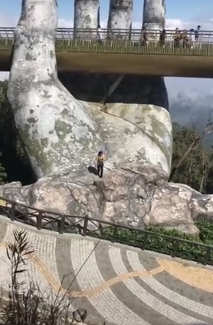 Du khách trèo hẳn ra bàn tay phía dưới Cầu vàng Sun World Bà Nà Hills để chụp hình sống ảo. Ảnh: Chụp màn hình.