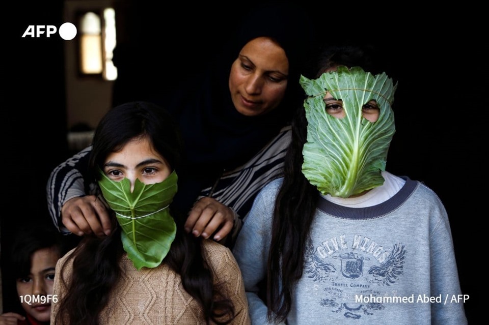 Để vui đùa, một bà mẹ Palestine cho các con gái đeo khẩu trang từ lá bắp cải, tại Beit Lahia phía bắc Dải Gaza, ngày 16.4. Ảnh: AFP