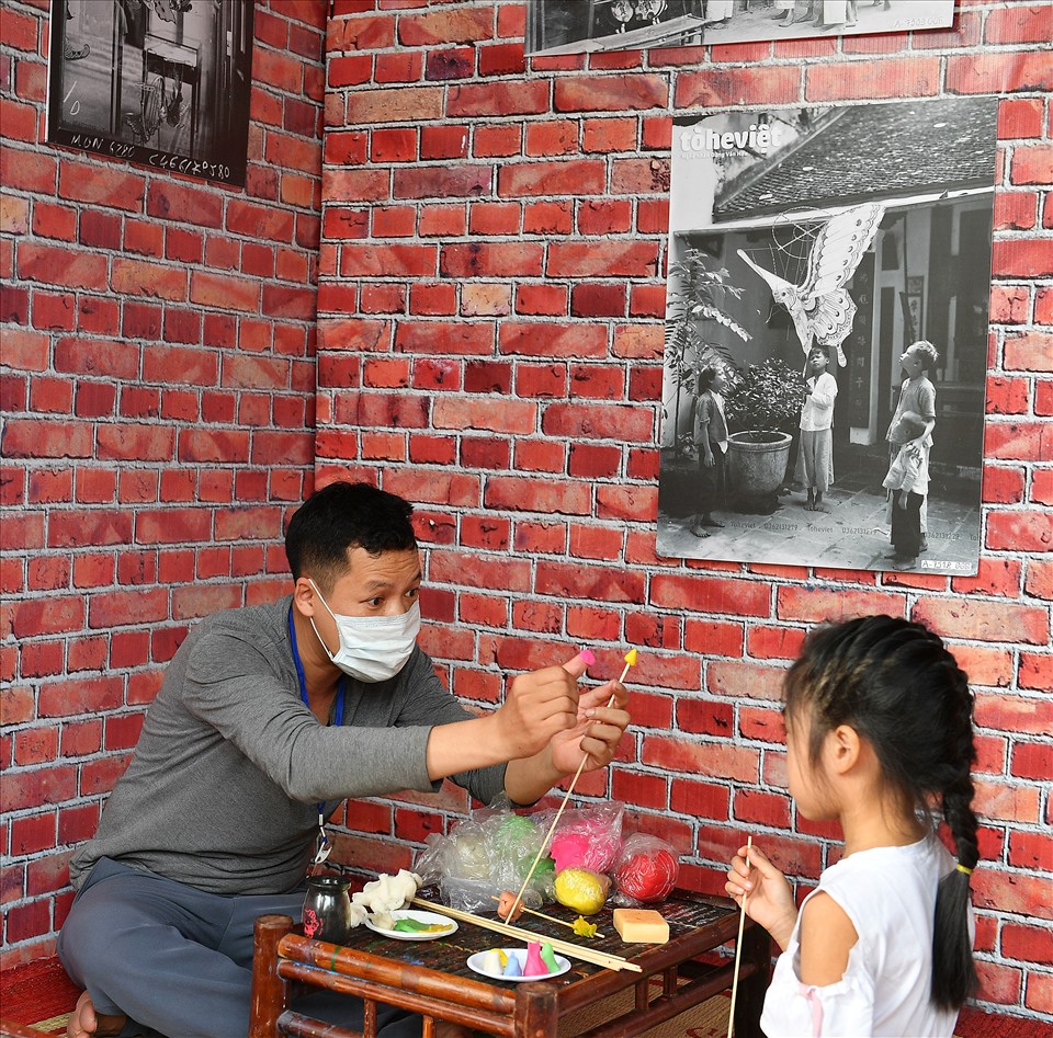 Nghệ nhân Đặng Văn Hậu chỉ dạy một trò chơi dân gian cho em bé.