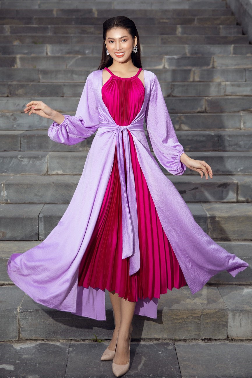 Á hậu Ngọc Thảo nổi bật với set đồ bao gồm áo choàng màu tím và váy yếm xếp ly màu đỏ.