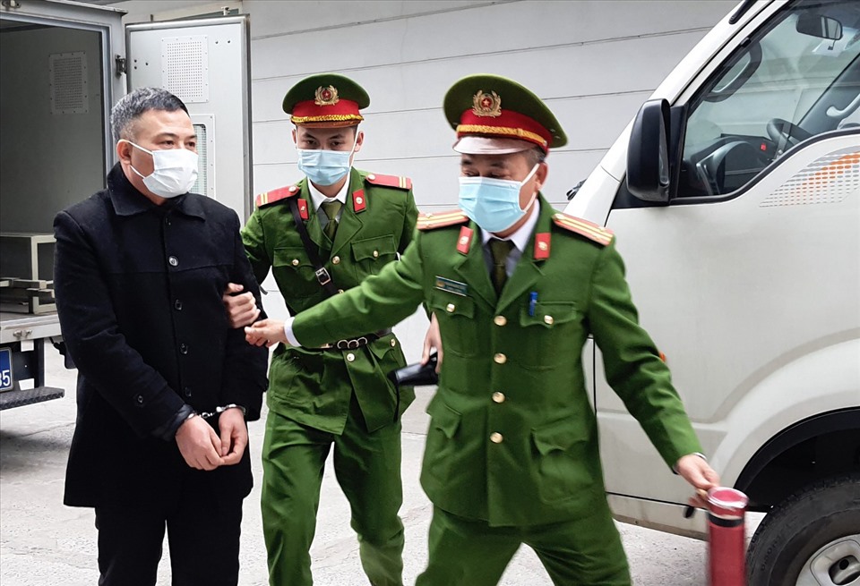Trong khi các bị hại làm thủ tục vào phiên toà, Lê Xuân Giang (áo đen) - bị cáo buộc chủ mưu cùng 6 đồng phạm chiếm đoạt tiền của hơn 68.000 nhà đầu tư, số tiền hơn 1.100 tỉ đồng. Ảnh: V.Dũng.